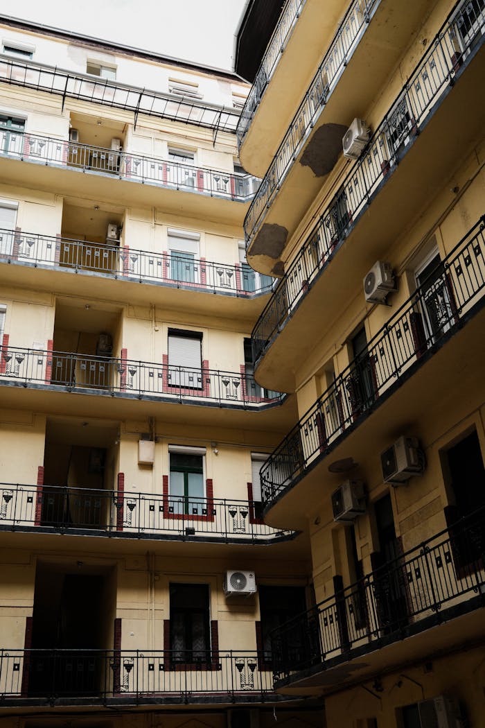 View of a multi-story urban apartment building with balconies and air conditioning units in Budapest.